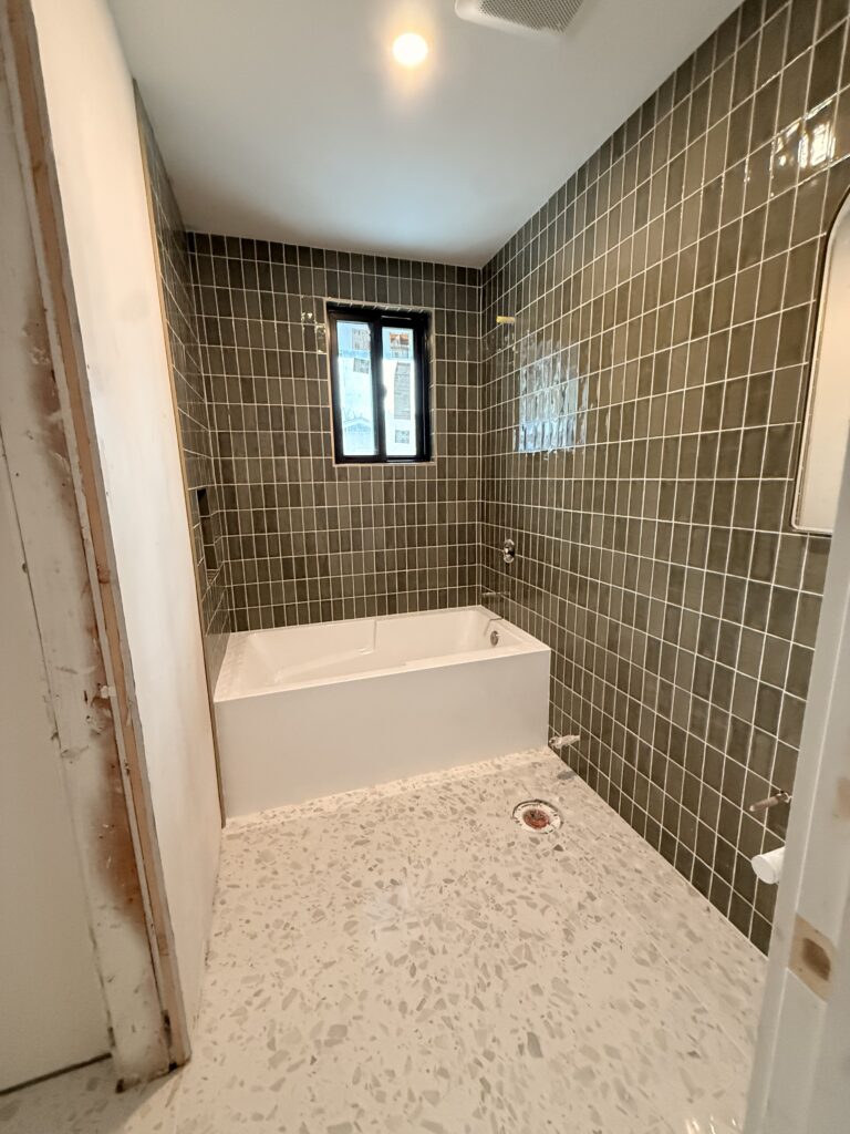 Modern bathroom under construction with tiled walls and terrazzo floor.